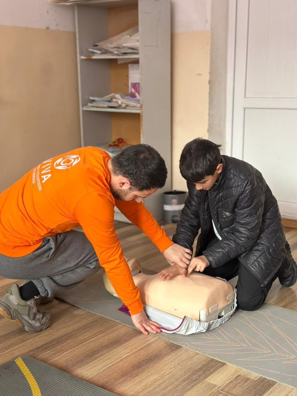 VIVA volunteer teaching a young participant CPR during first aid training in Armenia